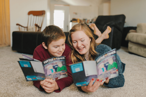 A mother and her young son on a rug and reading a "Tuttle Twins" book together.