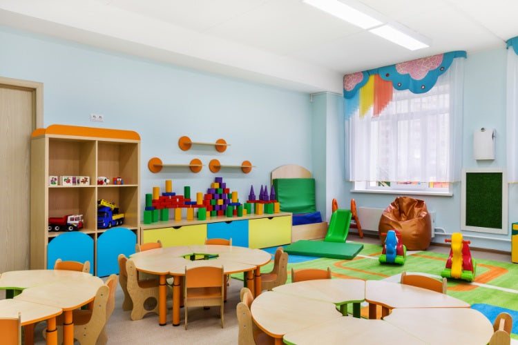 Empty preschool classroom with colorful furniture and toy storage.