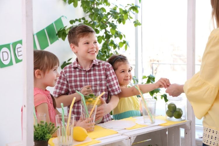 Children running a lemonade stand indoors together.