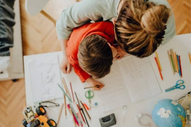 Parent helping child with homework at a study desk.