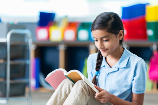 Middle school student reading a book at school.
