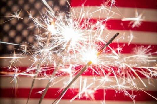Sparklers glowing in front of an American flag during a Fourth of July celebration.