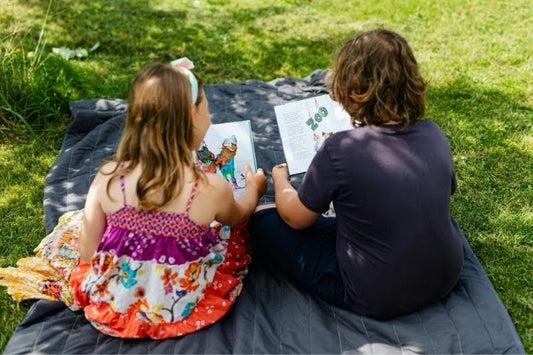 Children reading books outdoor.