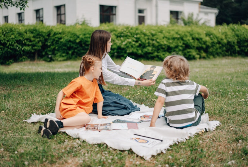 Kids learning outdoors during homeschool reading time.