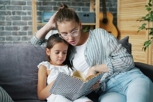 Mother and daughter reading a book together at home.