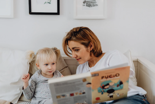 Mother reading book with child during homeschooling.