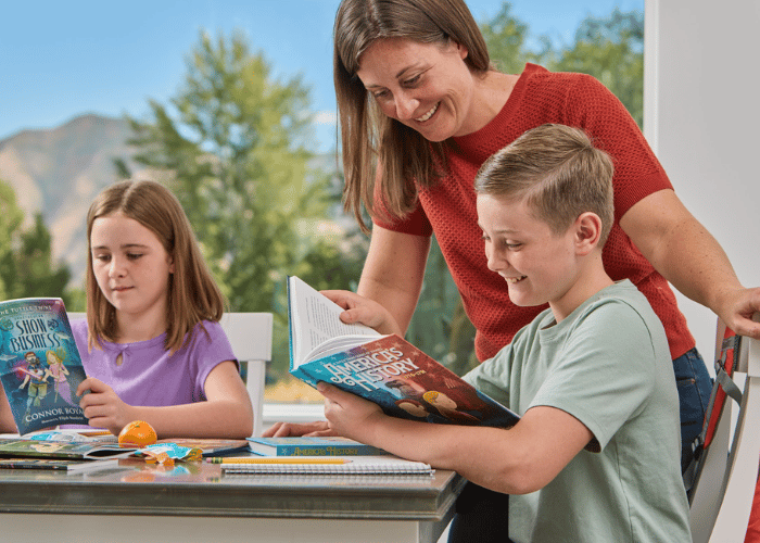 Mother helping children read books during homeschooling.