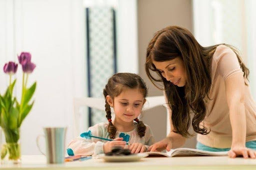 Mother helping her daughter with a homeschool reading lesson.