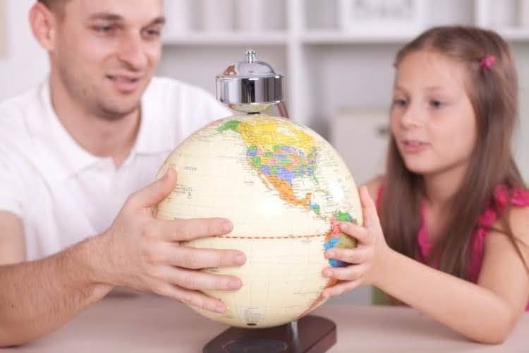 Father teaching his daughter world history using a globe.