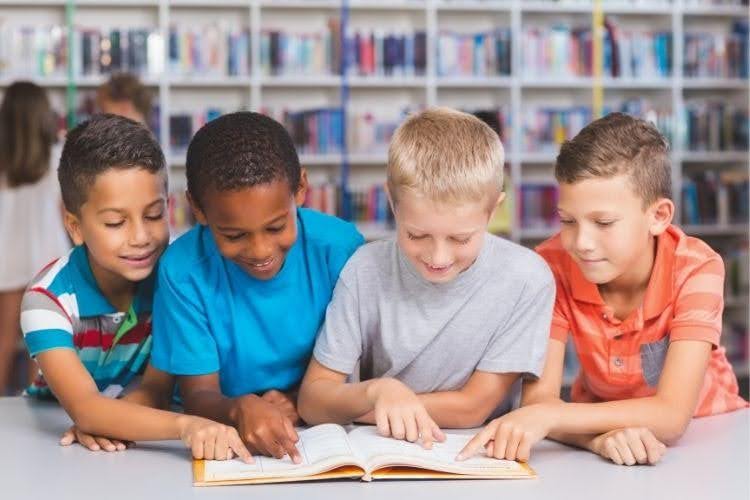 Young students gathered around a book during a collaborative reading activity.